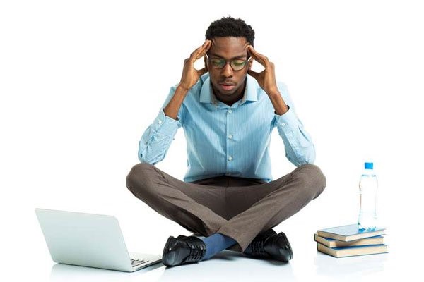 Man sitting on floor with laptop and books