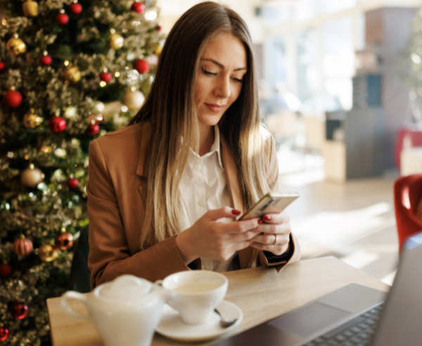 Woman sitting at computer with Christmas tree behind her